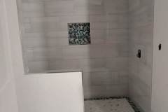 Bathroom tile renovation with stylish patterned flooring and wall tiling.