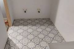 Up of a newly tiled kitchen corner with decorative patterned tiles and white walls, showcasing professional tile work by Grapme Tile Works Corp.