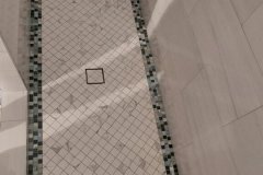 Up of a modern shower floor featuring mosaic border and small square tiles for a sleek bathroom look.