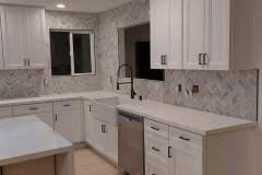 A spacious kitchen featuring white cabinets, a stylish tile backsplash, and modern fixtures for a clean, updated appearance.