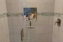A contemporary glass shower with a built-in niche, stylish fixtures, and neutral tile design for a luxurious bathroom.