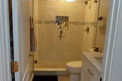 Bathroom with beige tiles, glass shower, and white vanity for a sleek look.