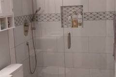 Elegant bathroom with white tiles and decorative border detail.