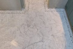 Beautiful marble floor with detailed border pattern in a home hallway, showcasing expert tile installation by Grapme Tile Works.