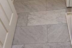 Up of marble-style bathroom floor tiles installed by Grapme Tile Works in a residential setting.