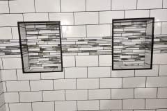 Up of a tiled wall featuring two inset niches with mosaic tile accents, showcasing high-quality craftsmanship and design.