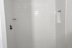 Elegant white tiled shower with a minimalist design and built-in niche for toiletries.