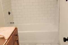 Bathroom shower with classic white subway tiles and hexagon floor tiles, showcasing quality tile work by Grapme Tile Works Corp.