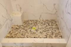Close-up of a pebble tile shower floor showcasing natural stone textures and craftsmanship.