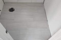 Up of newly installed light gray tile flooring in a bathroom or hallway space.