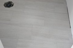 Up of a sleek, tiled bathroom shower floor with pebble accents and clean grout lines.