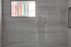 Interior view of a tiled wall with a small window, showcasing high-quality tile work by Grapme Tile Works Corp.