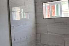 Contemporary bathroom shower featuring large gray tiles and a sleek, minimalist design.