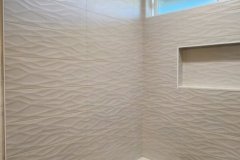 Up of stylish textured wall tiles with a built-in niche and terrazzo flooring in a modern bathroom.