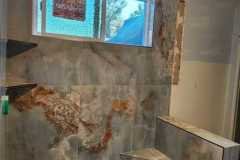 Modern bathroom with custom marble shower wall and pebble stone floor installed by Grapme Tile Works.