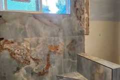 Interior bathroom featuring stone tile walls and pebble floor for a modern, durable finish.