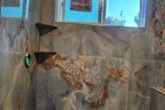 Elegant bathroom shower with stone tiles and built-in seating.