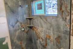 Modern marble tiled shower with built-in shelves, showcasing quality craftsmanship by Grapme Tile Works.