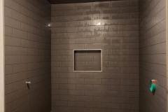 Contemporary shower space featuring dark tiles, a built-in bench, and a recessed niche for toiletries.