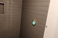 Close-up of a contemporary bathroom wall featuring large, smooth tiles and textured floor tiles for a stylish look.