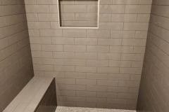 Stylish bathroom shower featuring beige subway tiles and a built-in niche for toiletries.