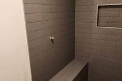 Close-up of a contemporary tiled shower with gray tiles and a recessed niche for toiletries.