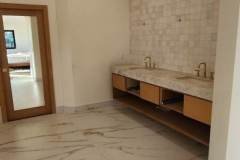 A luxurious bathroom featuring marble flooring and a tiled accent wall, showcasing high-end tile work by GRAPME TILE WORKS CORP.