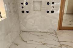 Beautiful marble tile bathroom wall with plumbing fixtures, showcasing high-quality craftsmanship by Grapme Tile Works.