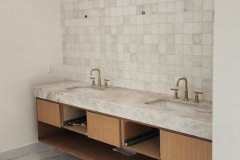 Elegant bathroom featuring a white tiled accent wall and a sleek double sink vanity with gold fixtures.