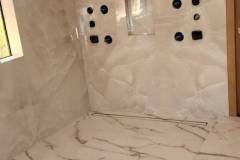 Elegant bathroom wall featuring large marble tiles and plumbing fixtures, showcasing high-quality tile installation.