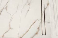 Modern bathroom featuring luxurious marble tiles and a stylish linear drain, showcasing high-quality tile installation by Grapme Tile Works.