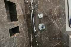 Elegant bathroom shower featuring brown marble tiles and modern fixtures.