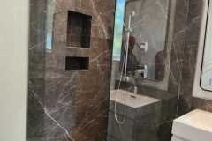 Stylish bathroom featuring a marble shower with glass walls, built-in niches, and modern fixtures.