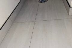 Up of a freshly tiled floor with grout lines and a drain in the corner.