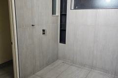 This image showcases a modern bathroom interior with light-colored tiles, a small window, and built-in wall niches, emphasizing clean design and funct.