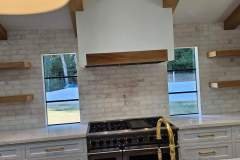 Stylish kitchen with white cabinetry, tile backsplash, and open wooden shelves for a modern look.