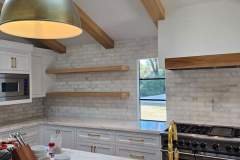 Contemporary kitchen design showcasing white cabinets, wooden open shelves, and a brick wall for a stylish look.