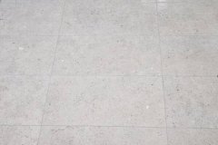 Clean tiled bathroom floor with a linear drain and mosaic wall tiles for a sleek look.