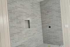Bathroom renovation featuring a sleek gray tile shower with a niche and bench for functionality and style.