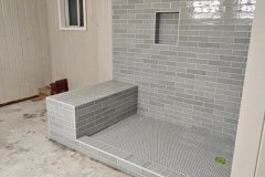 Beautifully tiled bathroom wall with niche and bench, highlighting professional tile work by Grapme Tile Works.