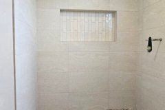 A contemporary shower area featuring large wall tiles and a textured pebble floor for a stylish bathroom upgrade.