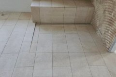 Contemporary bathroom with beige tiles on the floor and textured wall, showcasing elegant tile work by Grapme Tile Works Corp.