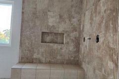 Interior view of a partially tiled wall with a built-in niche, showcasing professional tile work at Grapme Tile Works Corp.