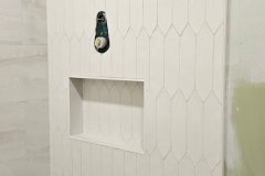 Interior view of a partially tiled wall with hexagon tiles and a built-in niche, showcasing professional tile installation.