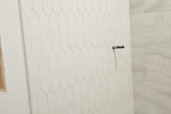 Modern white hexagon wall tiles being installed in a bathroom renovation.