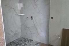 Bathroom renovation featuring marble wall tiles and pebble floor for a sleek, contemporary look.
