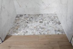 Modern bathroom with marble walls and mosaic shower floor.