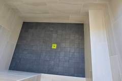 Close-up of a sleek, modern shower floor featuring dark gray tiles and beige wall tiles for a contemporary look.