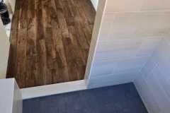A sleek, dark tile floor in a contemporary bathroom, showcasing professional tile installation by Grapme Tile Works.