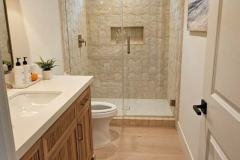 Spacious bathroom featuring a walk-in shower, beige tile walls, and a wooden vanity with modern fixtures.